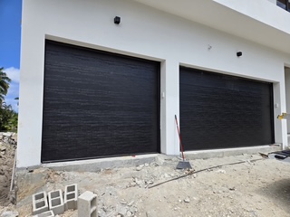 Two black woodgrain garage doors on new coastal construction