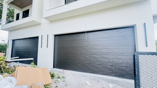 Two black woodgrain modern garage doors installed on a new South Florida home