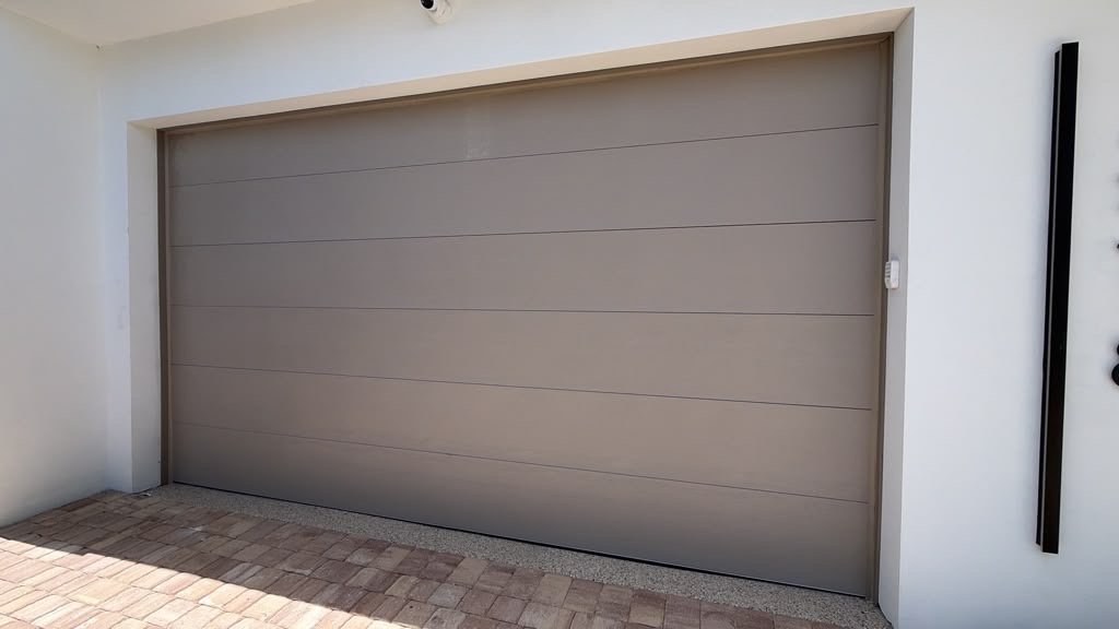 Sandstone flush panel garage door on a modern stucco home